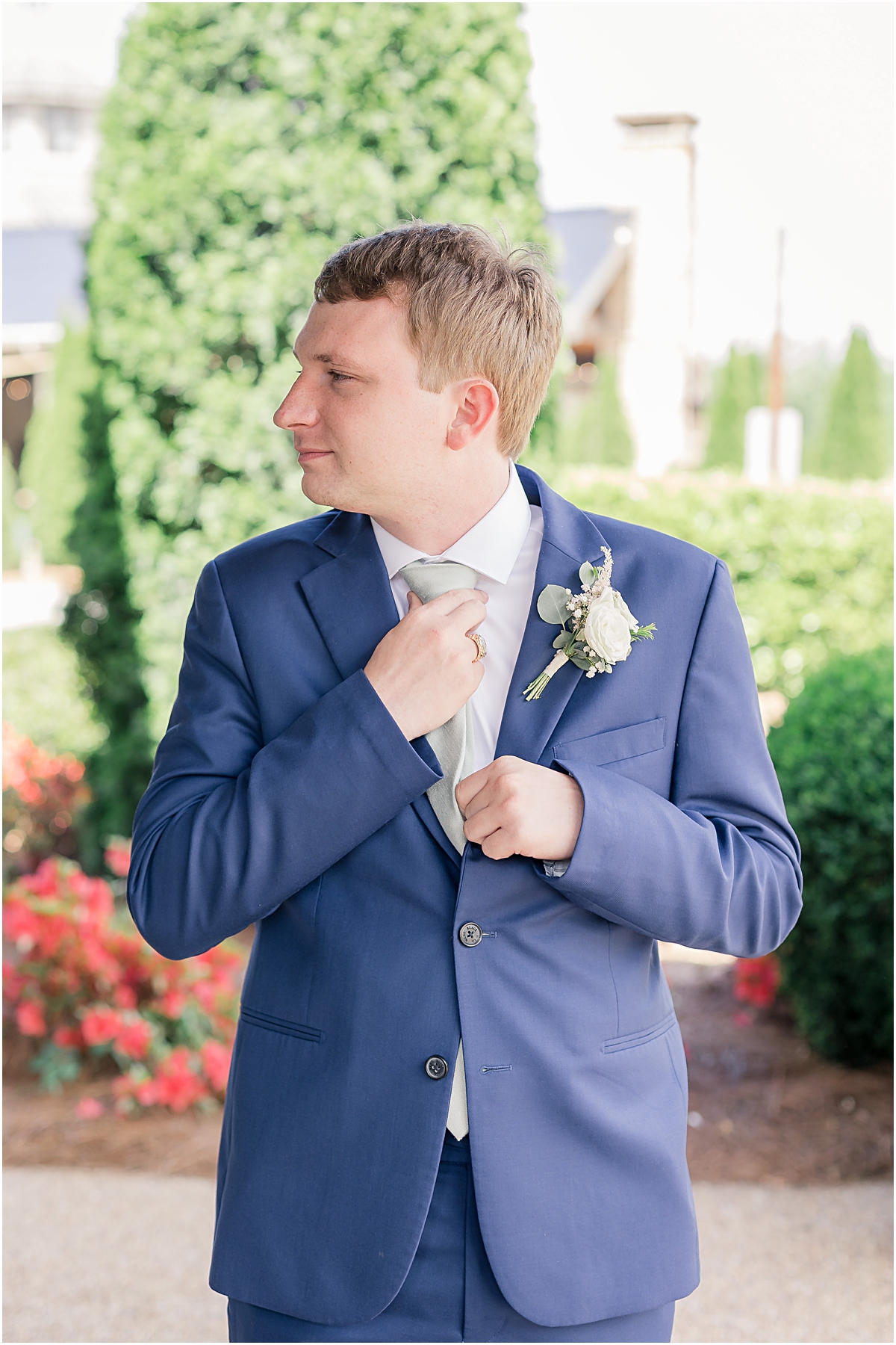 Groom in a blue suit straightening his tie 