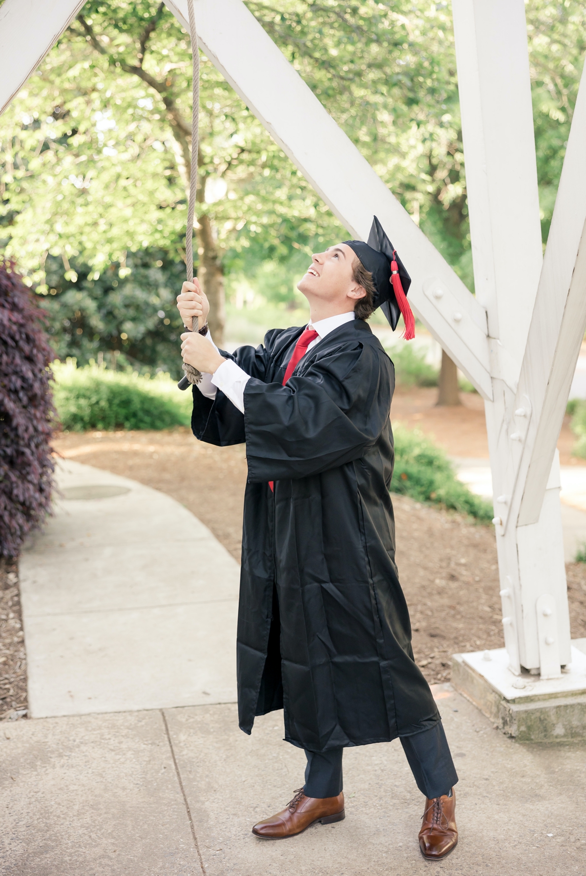 UGA graduate ringing the graduation bell in his cap and gown.