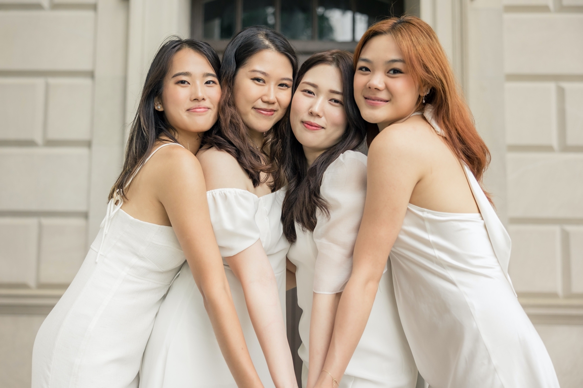 Four high school girls wearing nude dresses posing with their heads together during their senior session.