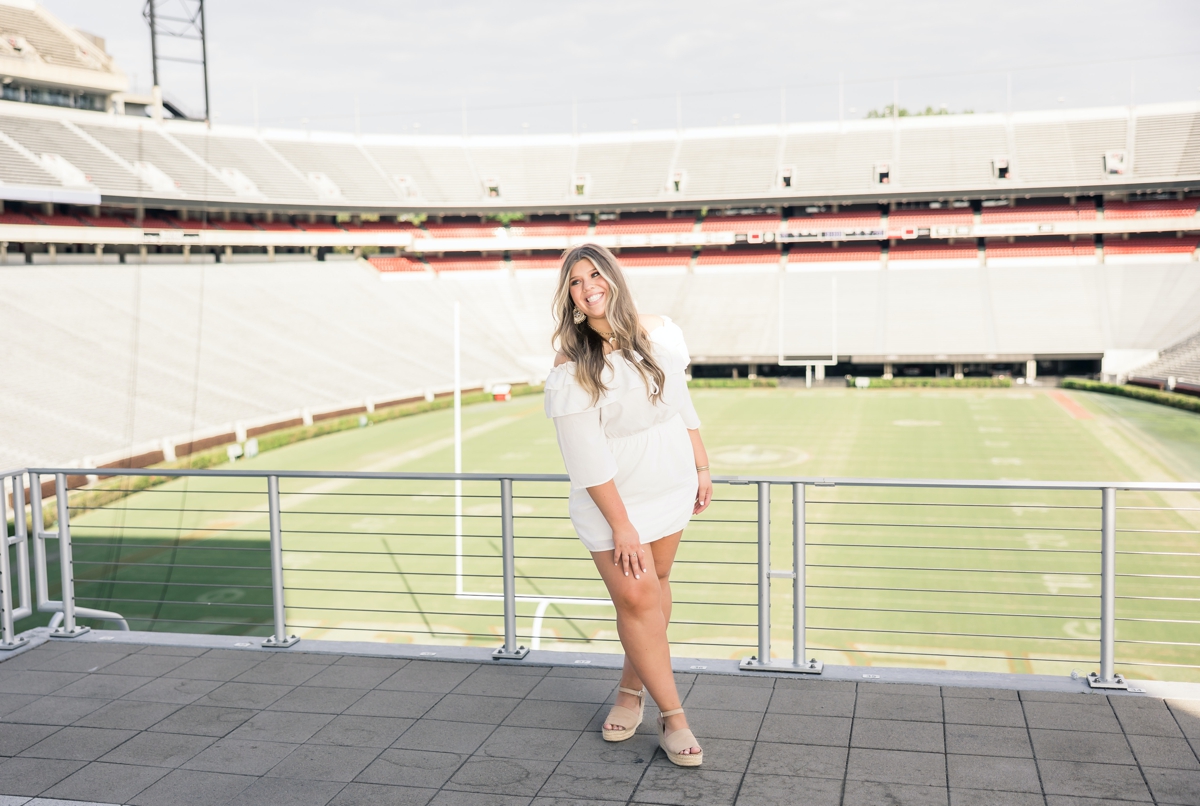 A college woman smiling in the football stadium during her senior session
