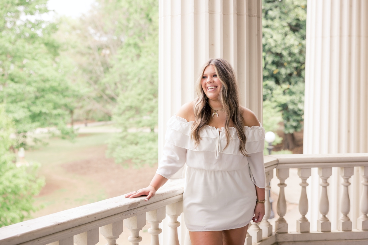 A college senior on the stone porch of a UGA campus building during her senior session.