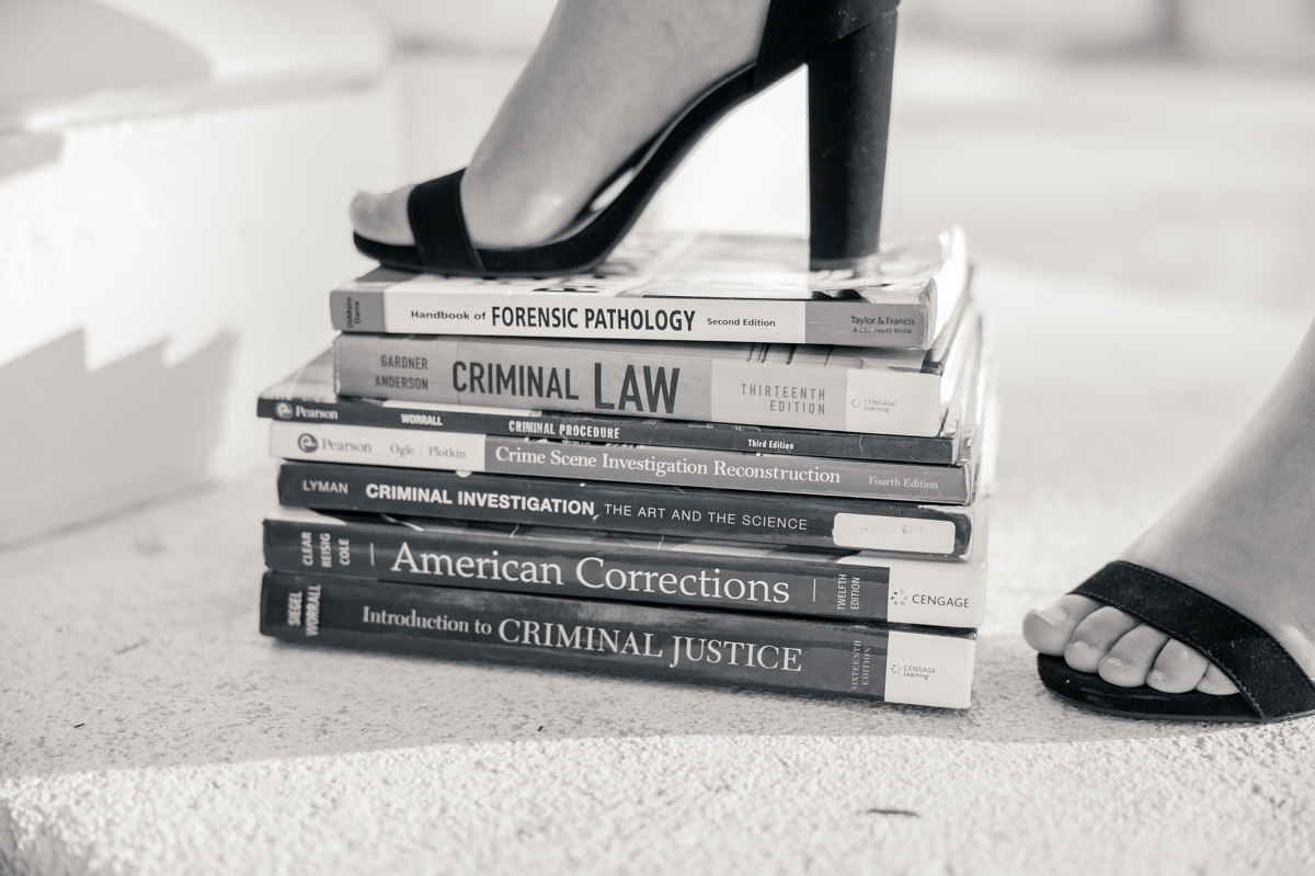 Black and white photo of a woman in high heels stepping on a book of pre law textbooks