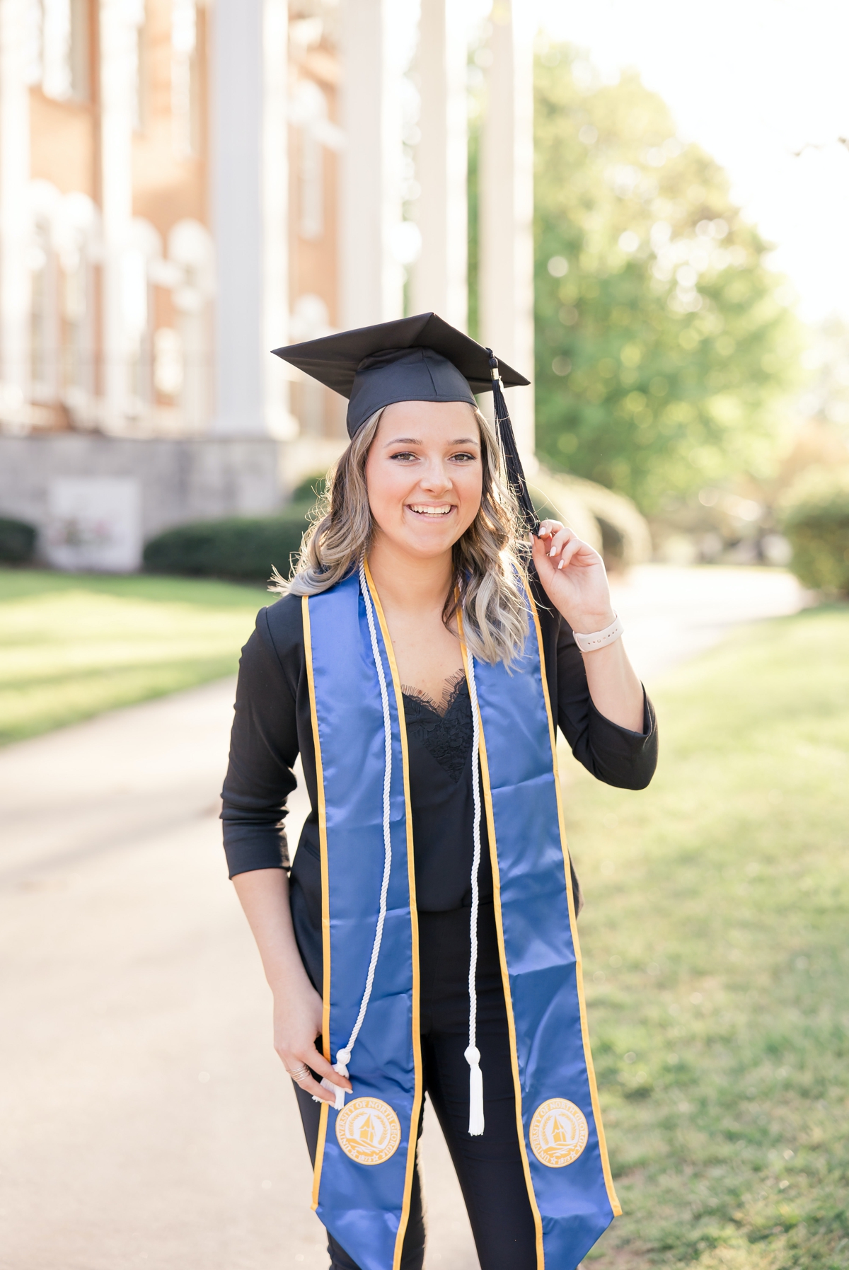 A woman wearing her graduation stole and playing with the tassel on her cap