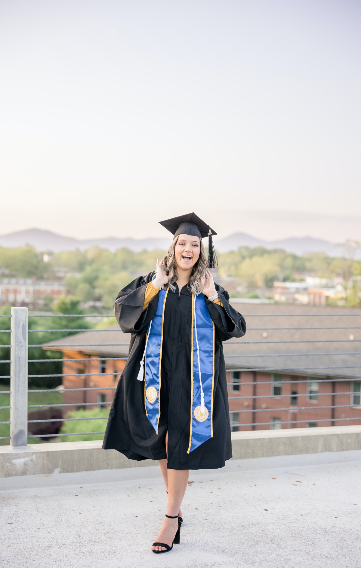 A woman laughing in her cap and gown during her graduation session