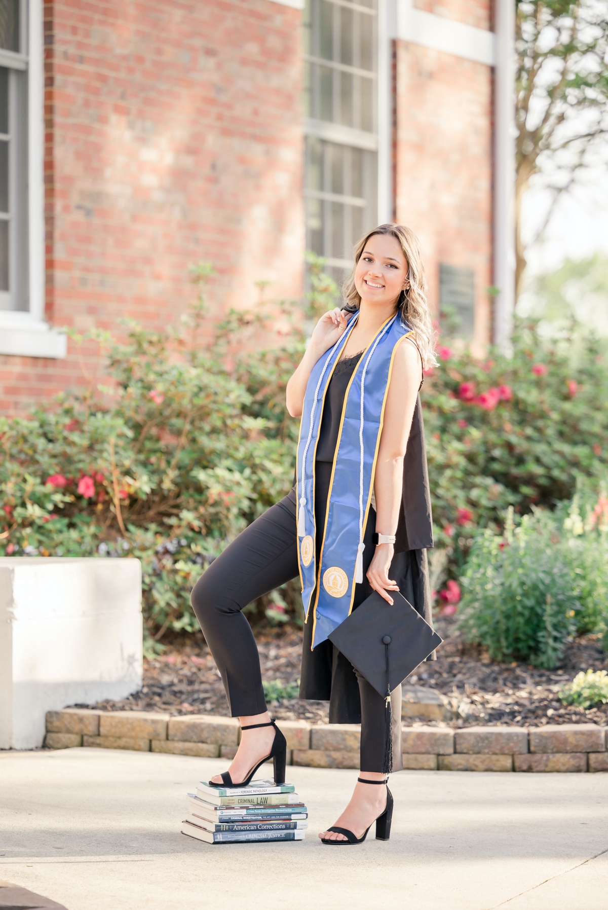 A University of North Georgia graduate standing on the stairs in front of a garden on campus.