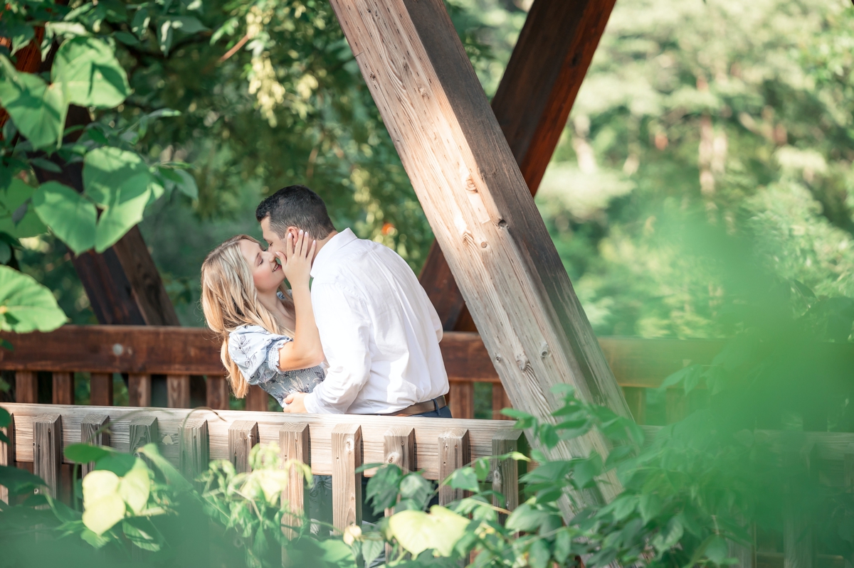 Julia and Taylor kissing on a bridge during their engagement session.