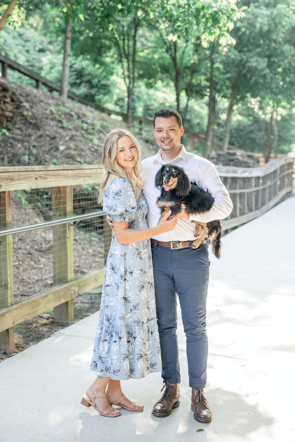 Julia and Taylor holding their dog on a bridge during their engagement session with Five Fourteen Photography.