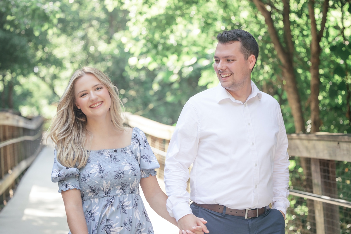 Julia and Taylor laughing while they hold hands and walk together during their engagement session with Five Fourteen Photography