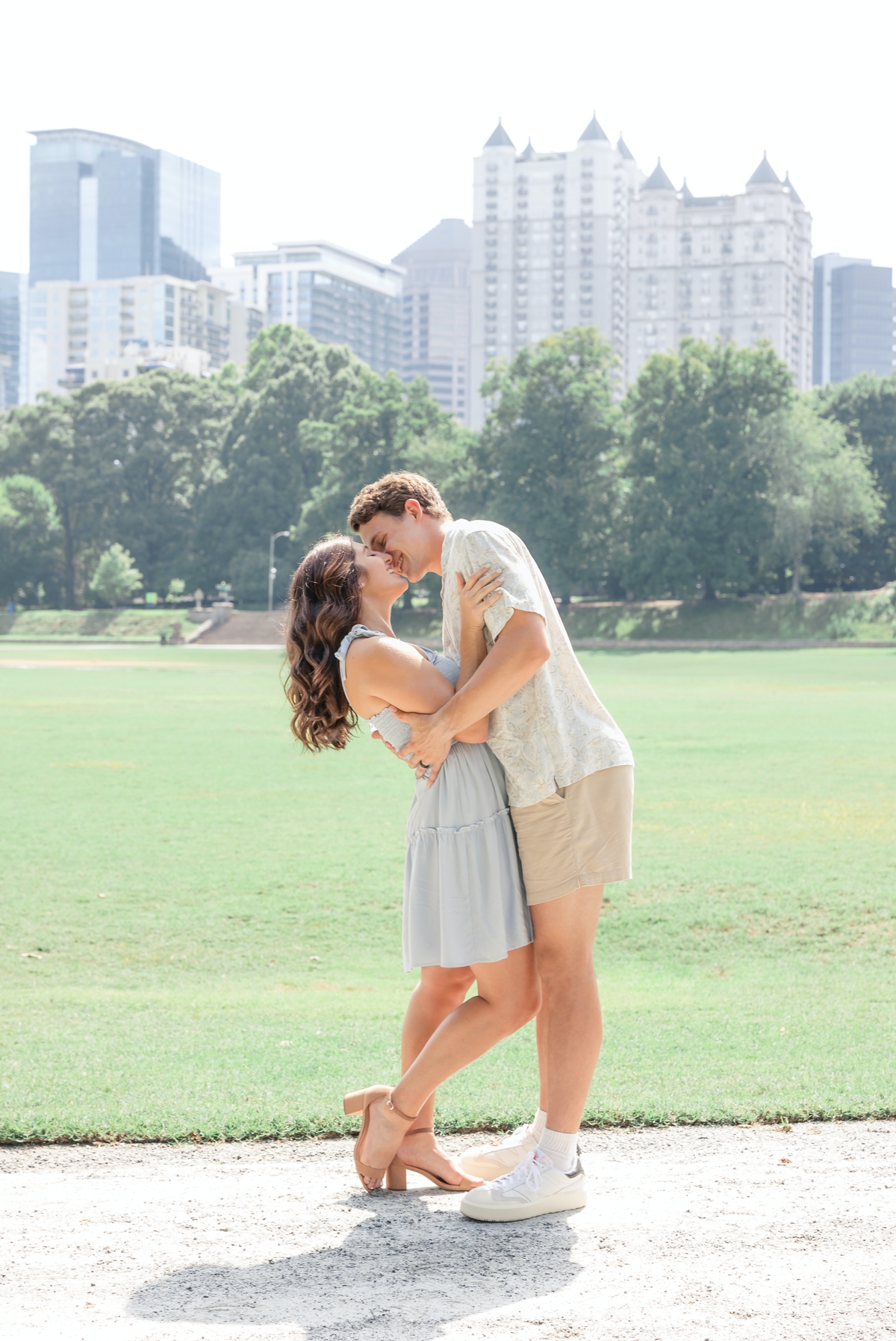 Isaac kissing Brooke while he dips her back in Piedmont Park overlooking the city.