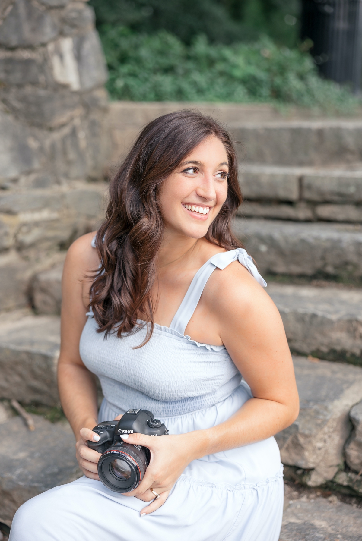Brooke sitting on stone steps at Piedmont Park while she holds her camera and smiles over her shoulder.