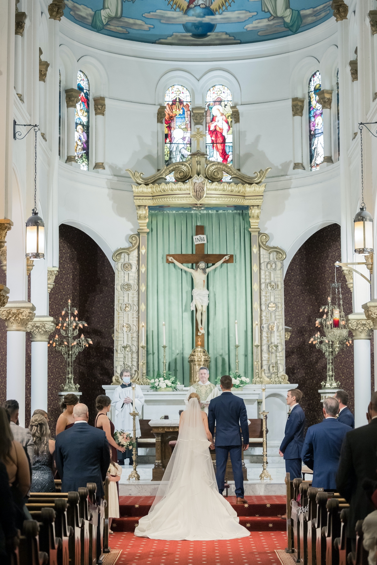 Rebecca and Josh standing at the altar of a Catholic church during their wedding ceremony.
