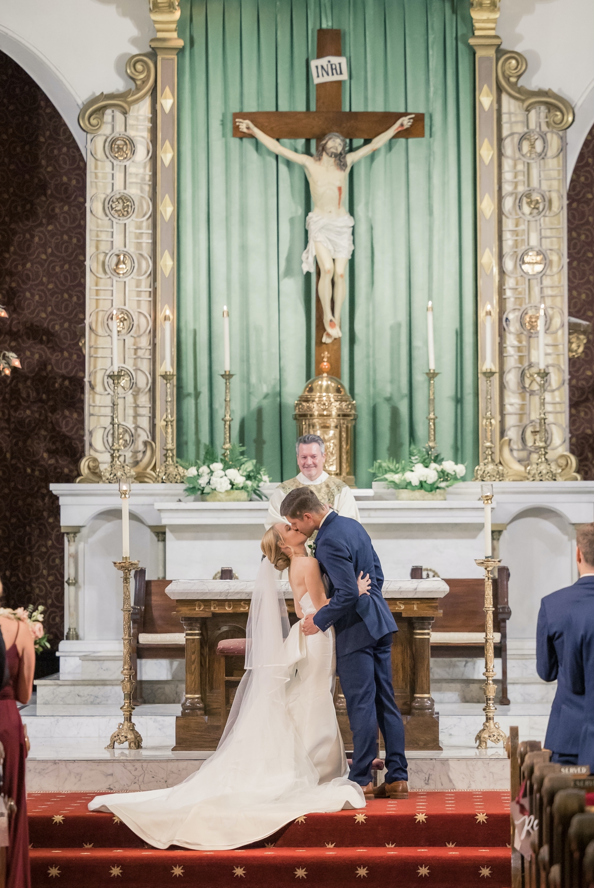 Rebecca and Josh kissing for the first time as husband and wife at the altar of a Catholic Church on their wedding day.