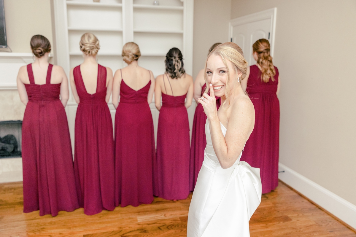 The bride smiling behind her bridesmaids during her first look.