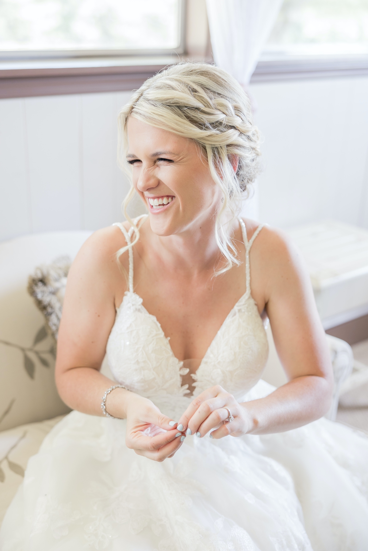 Grace laughing off in the distance with her eyes crinkling as she holds her earring in her hand on her wedding day at Walters Barn.