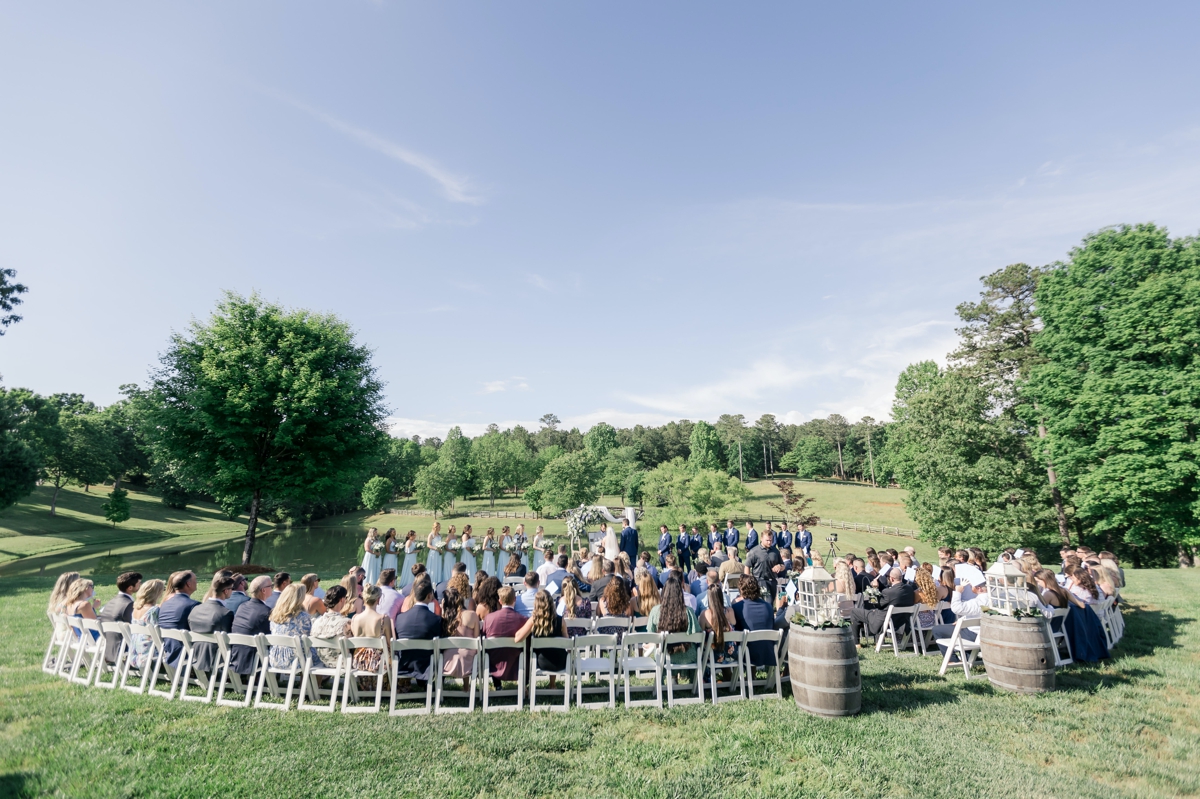A pulled back look at Chris and Grace's wedding ceremony with all of their guests looking on.