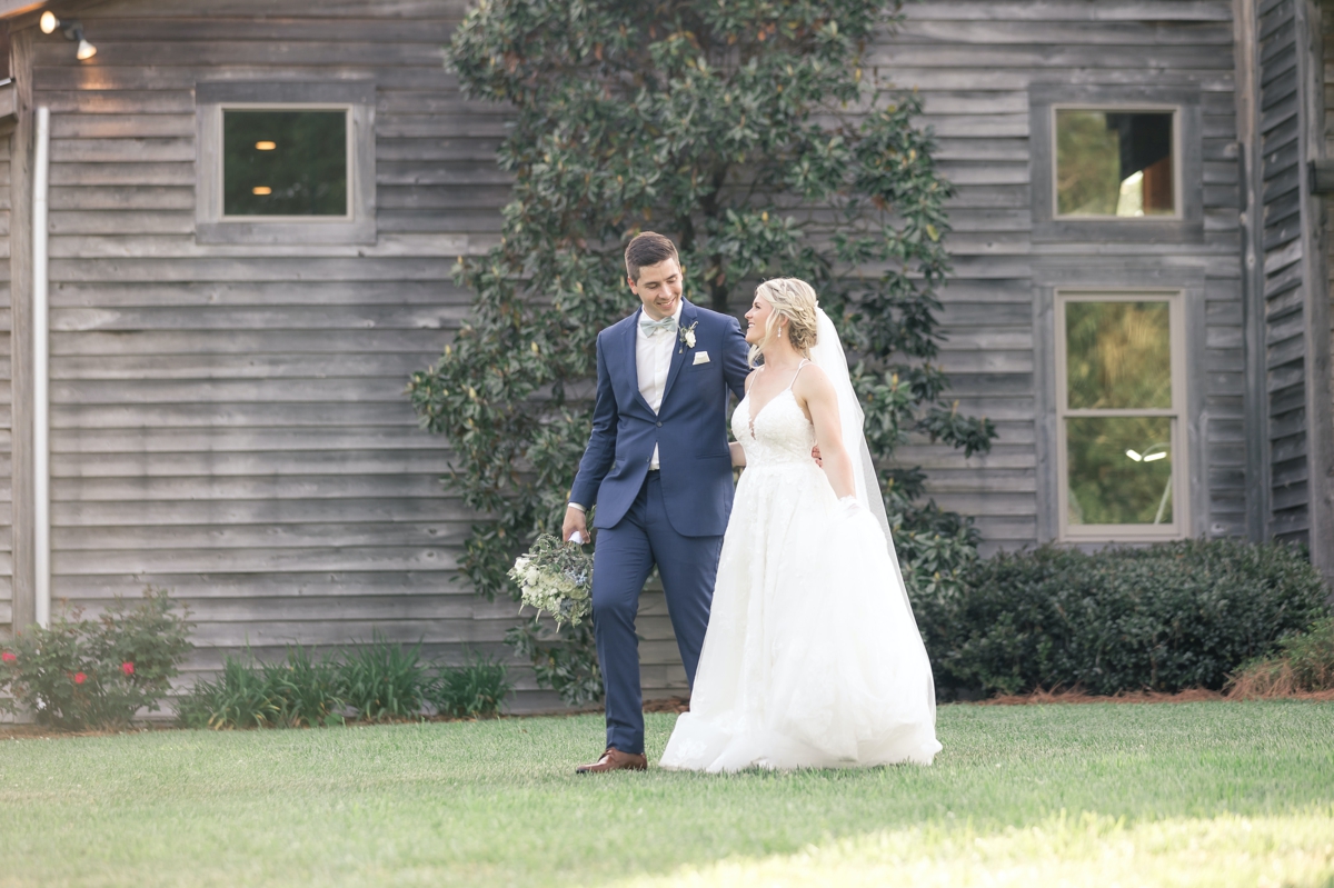 Grace and Chris walking hand in hand on their wedding day in front of Walters Barn.