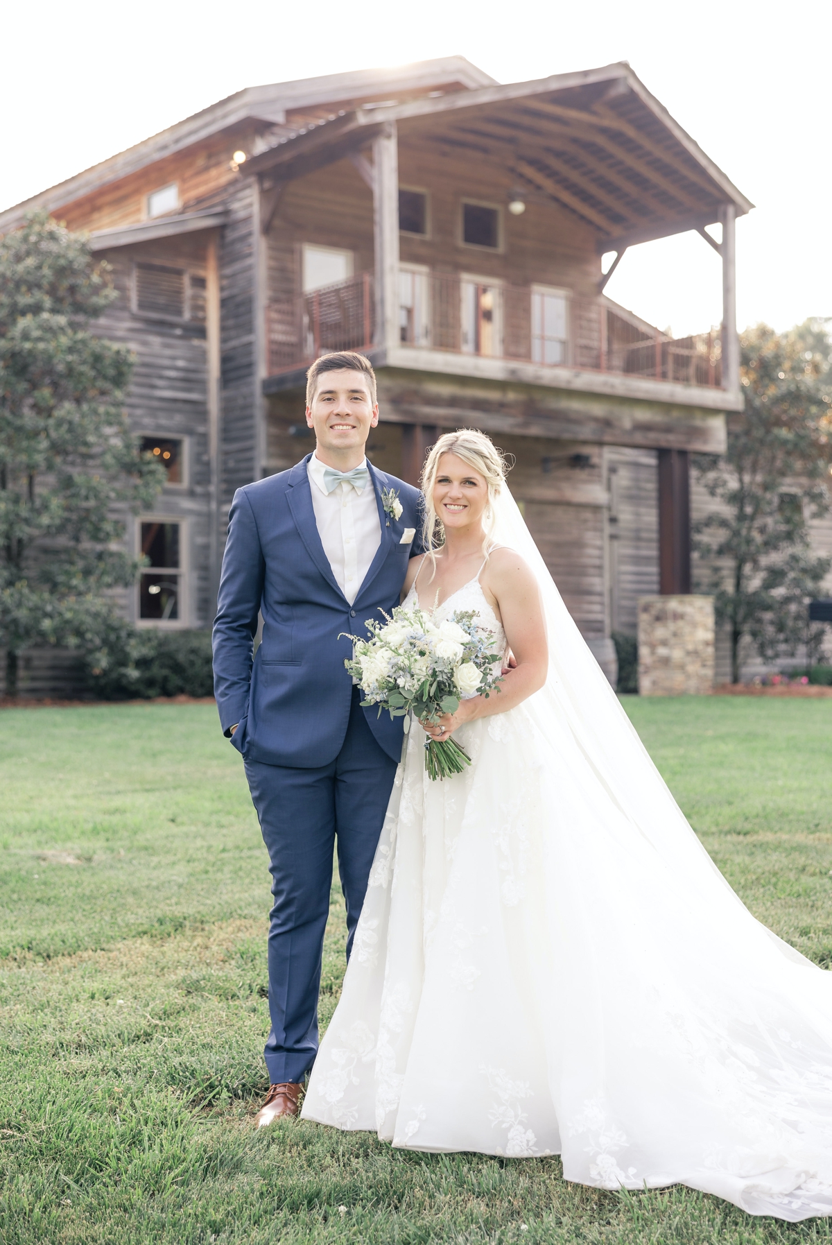 Grace and Chris smiling on their wedding day in front of Walters Barn in Lula GA