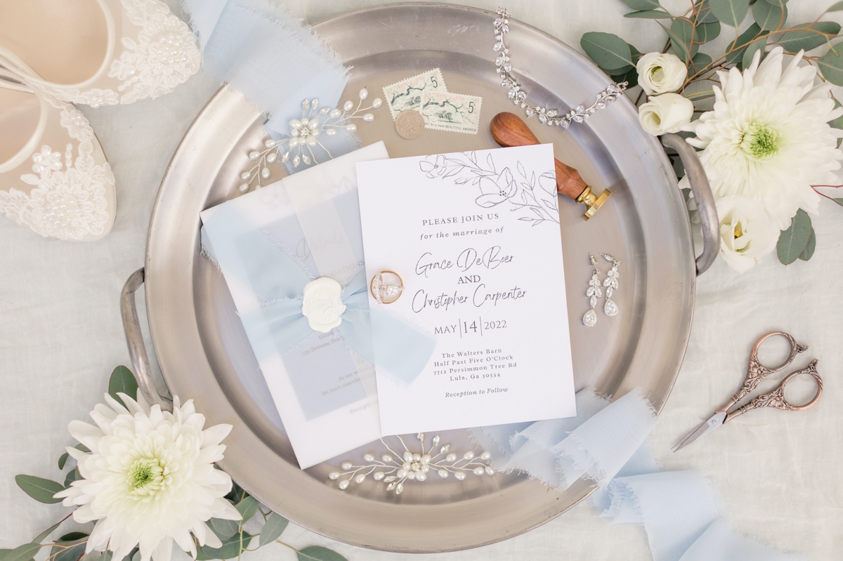 Detail photo of Chris and Grace's wedding invitations on a silver tray with their other wedding day details.