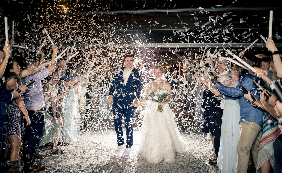 Chris and Grace walking through a wall of confetti during their wedding day exit at Walters Barn in Lula GA