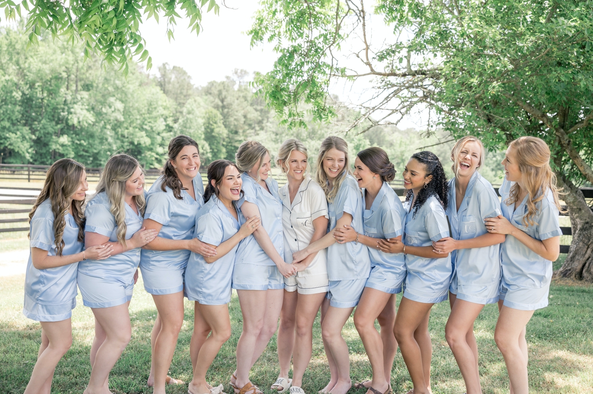 Grace holding hands and laughing with her bridesmaids on the lawn of Walters Barn in Lula GA on her wedding day.