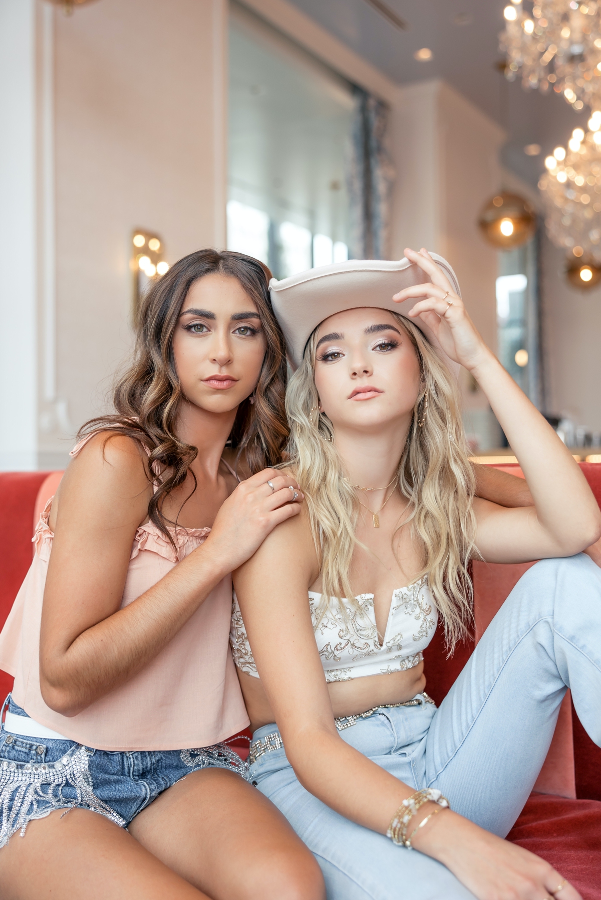 Jules and Eva sitting on a couch during their best friend senior session at The Graduate. 