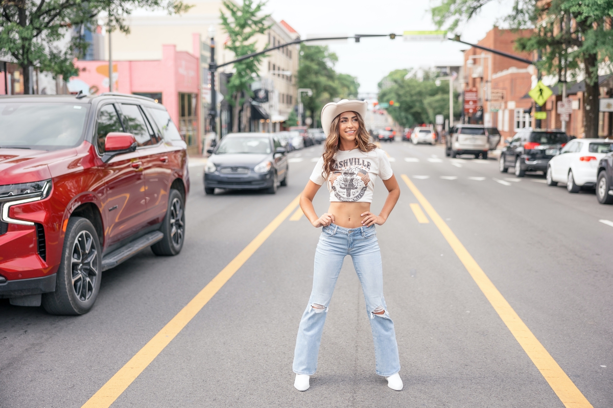 A brown haired senior standing in the middle of Broadway during her best friend Nashville senior session.
