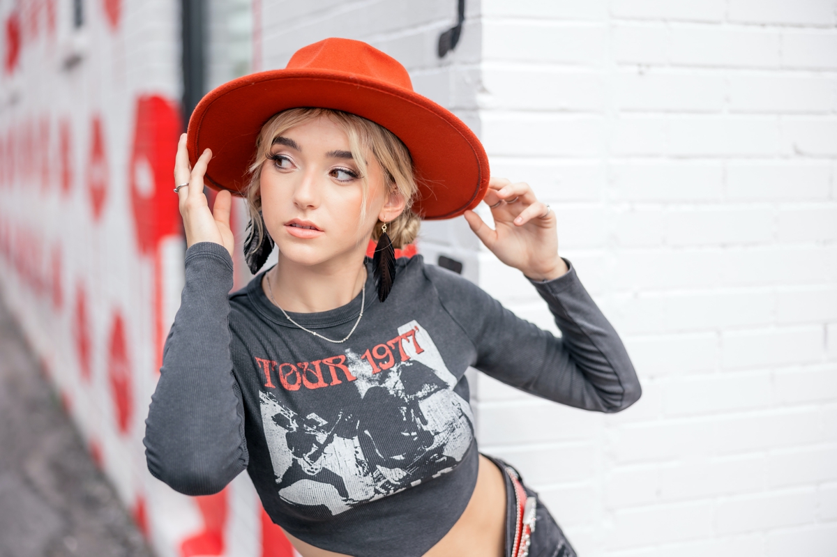 A blonde haired senior girl in a red hat.