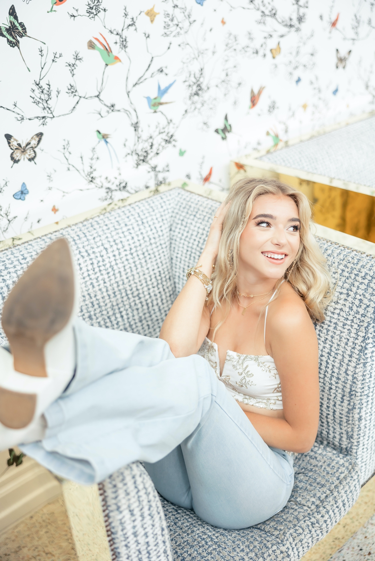 A blonde senior relaxing in a chair at The Graduate in Nashville during her senior session.