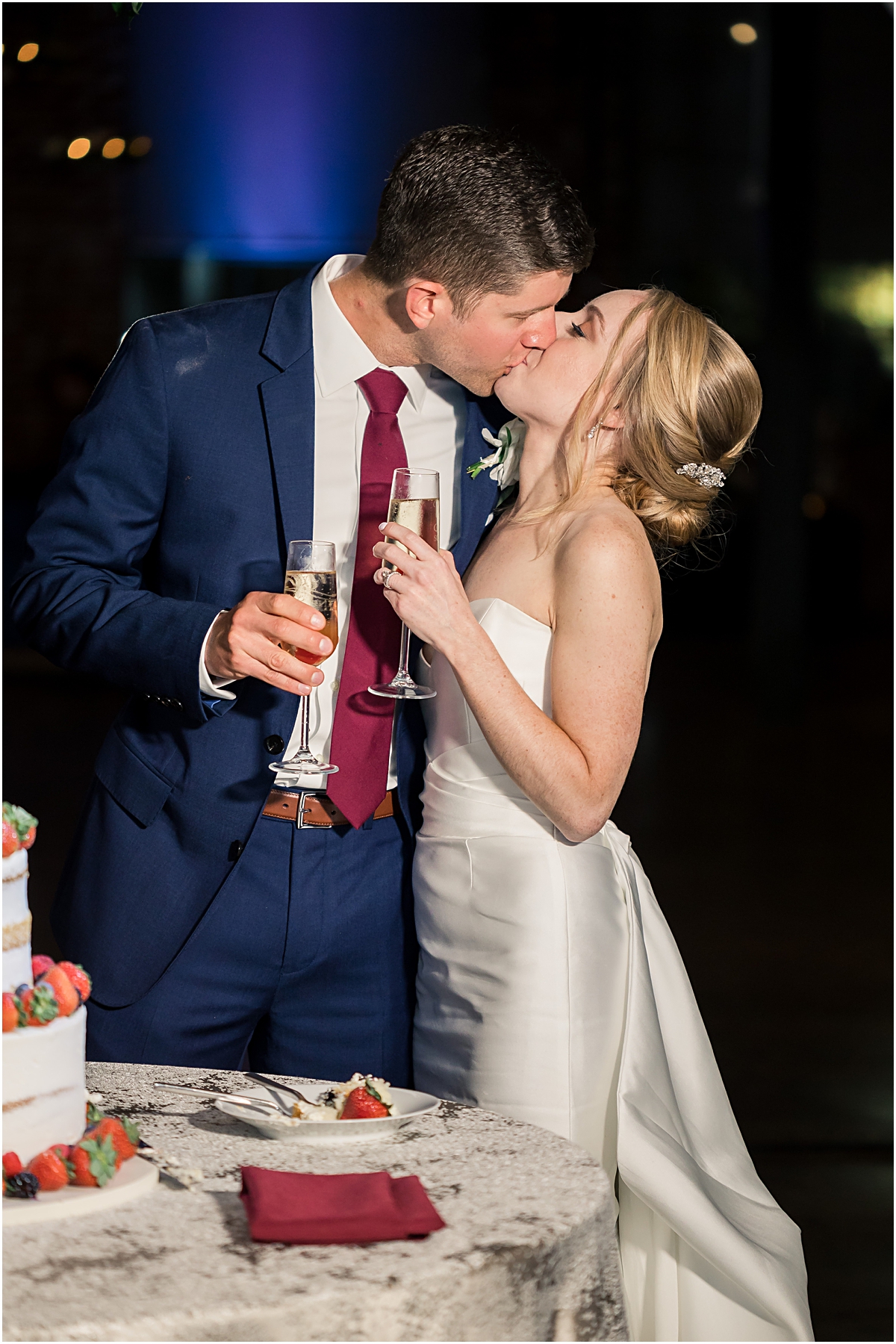 rebecca and john kissing while holding glasses of champagne during their wedding reception at a georgia wedding venue