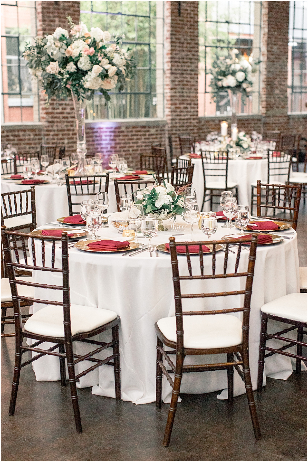 circle reception dining table with floral and candle centerpieces and maroon place settings