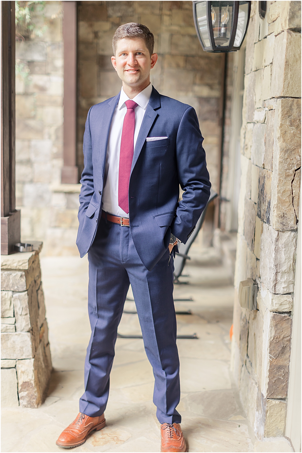 Groom portrait of John on his wedding day at the Foundry at Puritan Mill wearing a navy blue suit with maroon tie and brown dress shoes