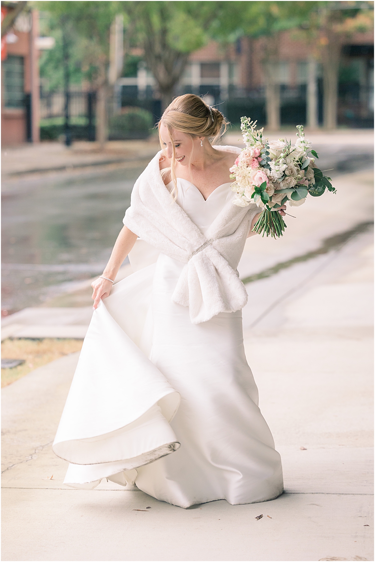 Rebecca swinging her bridal dress around while she wears a white fur cape and holds her bridal bouquet at the Foundry at Puritan Mill
