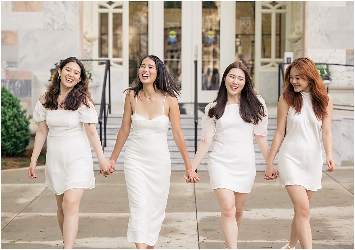 4 girls at Emory University in different styles of white dresses walking towards Emory University Senior Photographer